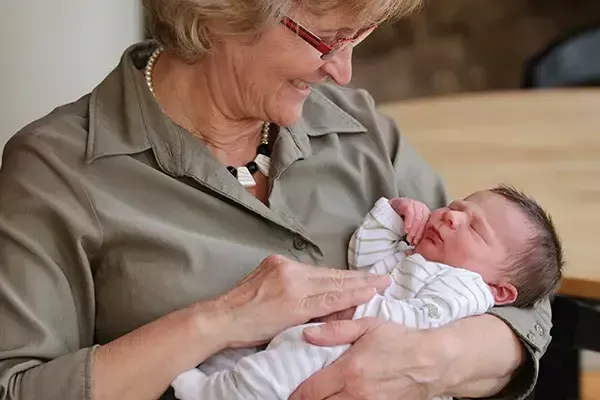 Grandmother holding and smiling at a new grandbaby