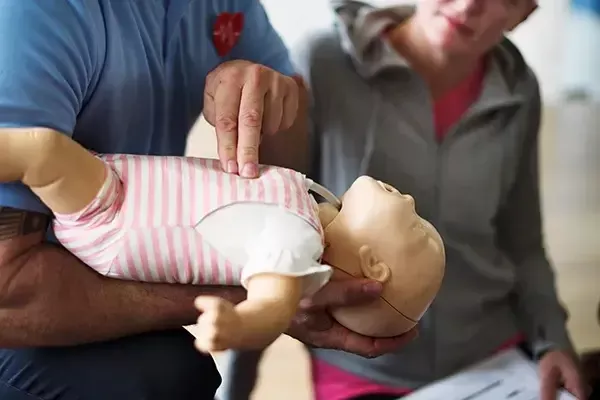 teacher showing someone how to do cpr on a mannequin